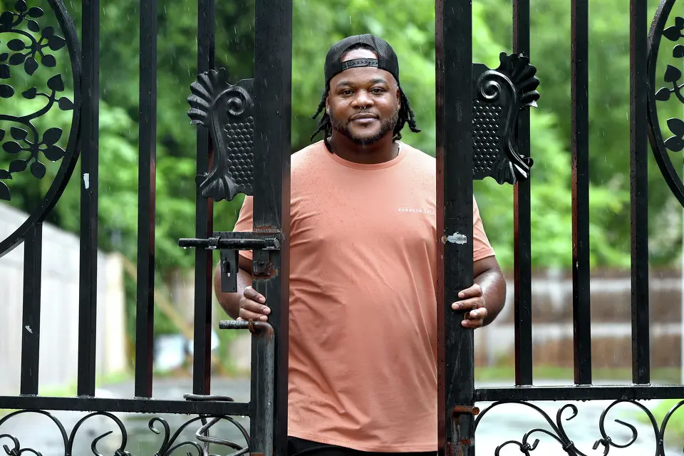 Marquis Jackson, who served years in prison for a wrongful murder conviction before his exoneration in 2018, at the driveway gate of his rental property in New Haven in 2025.