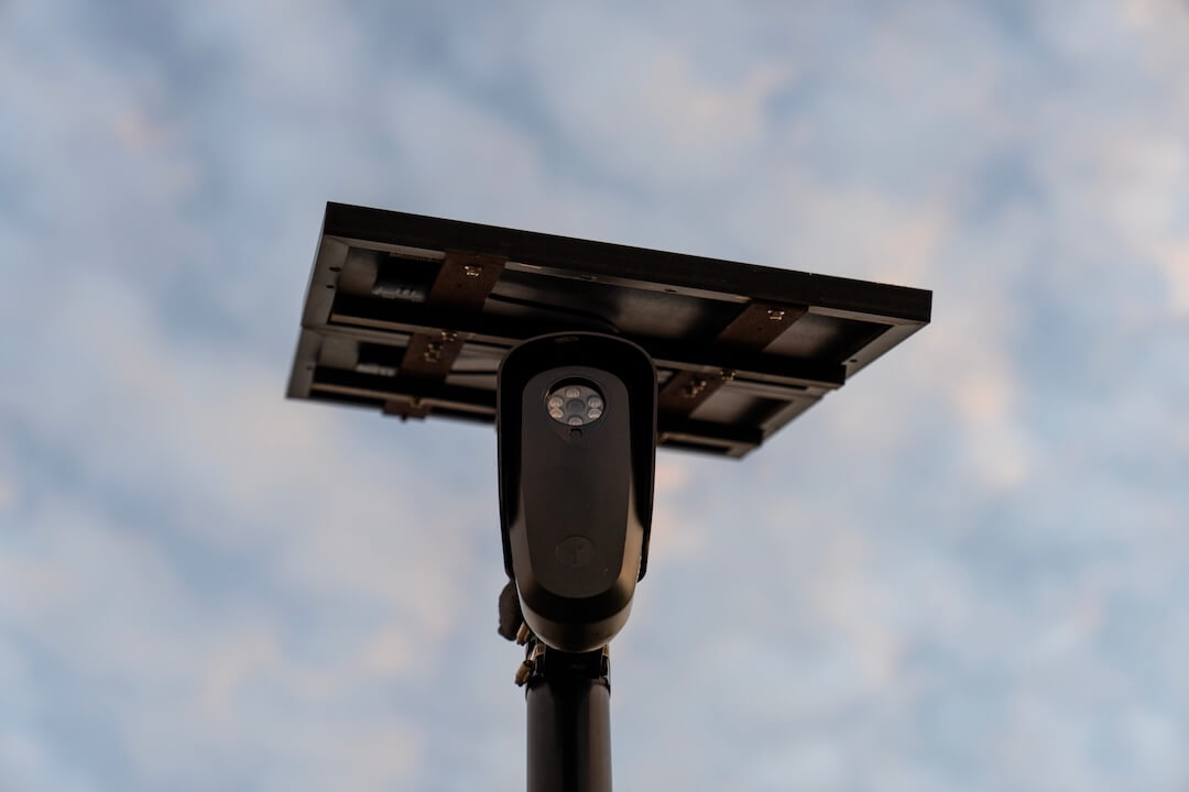 A Flock Safety automatic license plate reader mounted on a pole beside a public road.