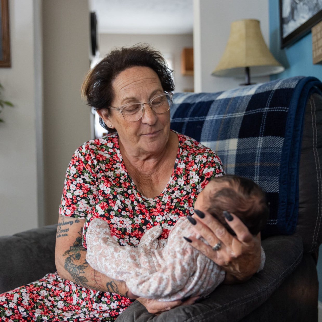 Ms. Smith holds a baby while sitting on an armchair.